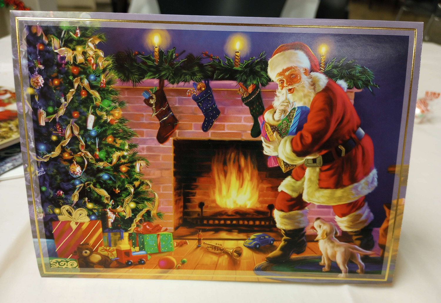 A sinister Santa Claus is seen shushing a small dog by a roaring fire.